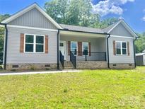 Charming single Gathering home featuring gray siding, brick foundation, wooden shutters, and a well-manicured lawn at 325 Jordan Ave, Salisbury, NC 28159