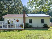 Charming one-story home featuring solar panels and a cozy front porch with table and chairs at 327 Downing St, Troutman, NC 28166