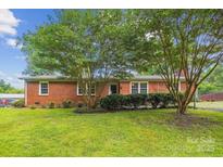 Charming red brick home featuring a well-manicured lawn, mature trees, and inviting curb appeal at 8706 Richardson King Rd, Waxhaw, NC 28173