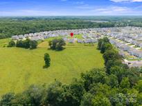 Expansive aerial view of a suburban neighborhood, showcasing a spacious green field and well-maintained homes at 117 Carmine Ct, Troutman, NC 28166