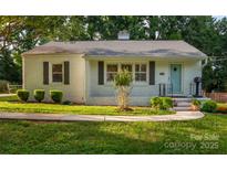 Charming single-story home featuring a light blue front door, gray shutters, and lush, green landscaping at 2115 Arnold Dr, Charlotte, NC 28205