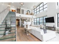 Bright living room featuring floor-to-ceiling windows, modern decor, and a glass staircase, offering city views at 222 S Caldwell St # 2203, Charlotte, NC 28202