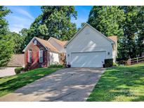 Inviting home with a brick facade, two-car garage, mature trees and a long driveway at 2620 Yarrow Rd, Charlotte, NC 28213