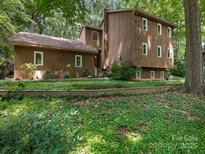 Two-story home featuring brown siding, multiple windows and a well-manicured front yard with lush greenery at 3310 Windbluff Dr, Charlotte, NC 28277