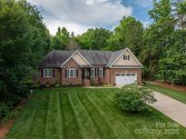 Charming brick home featuring a well-manicured lawn and an attached two-car garage at 7988 Golf Course N Dr, Denver, NC 28037