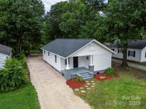 Charming house with a landscaped front yard, gravel driveway and gray painted porch at 1210 Cloninger Ave, Gastonia, NC 28052