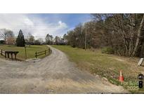 Long gravel driveway leading up to a home on a large, grassy lot with mature trees at 12143 Asbury Chapel Rd, Huntersville, NC 28078