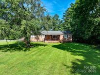 Charming single-story brick home with a lush green lawn and mature trees at 12143 Asbury Chapel Rd, Huntersville, NC 28078