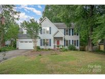 Charming two-story home with a well-manicured lawn, blue shutters, and a welcoming red front door at 13416 Kintyre Ct, Matthews, NC 28105