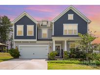 Charming two-story home with a well-manicured lawn and inviting front porch at 205 Falls Cove Dr, Troutman, NC 28166
