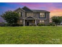 Charming two-story gray brick home with a manicured lawn and lush landscaping at 410 Alucio Ct, Matthews, NC 28104