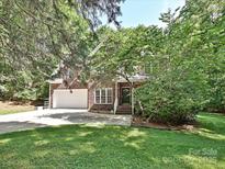 Two-story brick home featuring an attached two-car garage, well-maintained lawn, and mature trees for shade at 443 Hillcrest Dr, Harrisburg, NC 28075