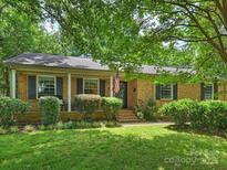 Charming brick home with a well-manicured lawn, classic shutters, and inviting front porch with an American flag at 5211 Londonderry Rd, Charlotte, NC 28210