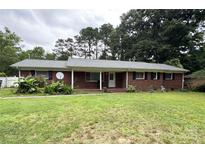 Charming brick home featuring a cozy covered porch and complemented by a beautifully landscaped front yard at 6539 Louglen Cir, Charlotte, NC 28212