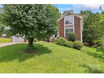 Beautiful brick home with a well-manicured lawn and mature landscaping, including a large shade tree at 10043 Elsenham Ln, Charlotte, NC 28269