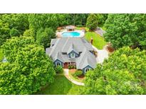 Beautiful home from above, showcasing a well-kept lawn, swimming pool, and mature landscaping at 1042 Heather Glen Dr, Matthews, NC 28104