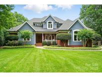 Charming two-story home with blue siding, brick accents, and a well-manicured lawn at 1042 Heather Glen Dr, Matthews, NC 28104