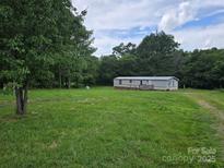 Spacious front yard with a manufactured home surrounded by lush green trees at 1150 Wyatt Grove Church Rd, Gold Hill, NC 28071