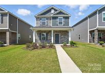 Charming two-story home with stone accents, gray shutters, well-maintained lawn and walkway at 125 Cedar Knoll Cir, Pineville, NC 28134