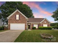 Charming brick home featuring a well-manicured lawn, attached garage, and a warm, inviting entrance at 133 Fontanelle Dr, Mooresville, NC 28115
