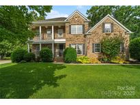 Charming two-story brick home with a well-manicured lawn, classic columns, and dark shutters at 1812 Mill Chase Ln, Waxhaw, NC 28173