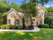 Charming brick home featuring a well-manicured lawn, mature trees, and classic architectural details at 2027 Brook View Ct, Matthews, NC 28104