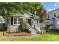 Charming brick home with landscaped front yard, inviting bench, and covered front porch at 3035 Florida Ave, Charlotte, NC 28205