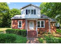 Charming brick home featuring a quaint front porch and mature landscaping at 317 Campus St, Charlotte, NC 28216