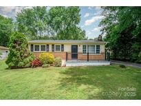 Charming single-story home featuring lush landscaping and a welcoming front porch with black railing at 4720 Randleman Rd, Conover, NC 28613