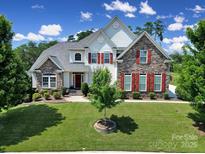 Beautiful two-story home featuring stone and siding, a well-manicured lawn, and red window shutters at 510 Placid Ct, Tega Cay, SC 29708
