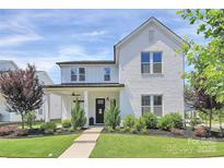 Charming two-story white brick home featuring a black door and well-manicured landscaping at 5129 Whitman Ave, Matthews, NC 28105