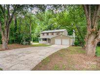 Charming two-story home featuring a two-car garage and a welcoming front porch nestled amongst mature trees at 7008 Wannamaker Ln, Charlotte, NC 28226