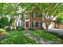 Charming two-story brick home featuring a lush lawn, mature trees, and a welcoming stone pathway at 7321 Harrisonwoods Pl, Charlotte, NC 28270