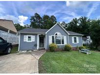 Charming one-story home with a well-manicured lawn, inviting entry and mature trees in the background at 7401 Merrily Ln, Charlotte, NC 28214