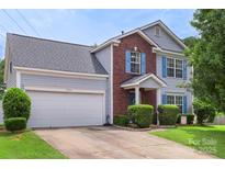 Charming two-story home with a brick facade, light grey siding, blue shutters, and a well-maintained front yard at 8904 Gerald Dr, Charlotte, NC 28217