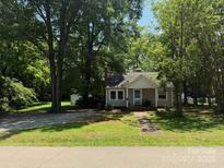 Charming one-story home with mature trees and inviting front porch, nestled in a serene, green landscape at 917 Tennyson Dr, Charlotte, NC 28208