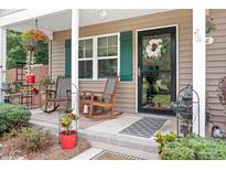Inviting front porch with rocking chairs, floral arrangements, and a welcoming wreath on the front door at 9716 Psalms St, Cornelius, NC 28031