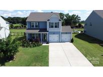 Two-story home with two-car garage, light blue siding, green grass, and well-maintained landscaping at 1019 Beacon Ave, Monroe, NC 28110