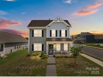 Charming two-story home with a welcoming front porch and well-manicured landscaping at sunset at 146 Kerri Dawn Ln, Locust, NC 28097