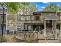 Two-story home with wood siding, balcony, stairs, and brick landscape feature at 1604 Sharon W Rd, Charlotte, NC 28210