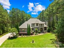 Beautiful stone and stucco home with lush landscaping and a circular driveway nestled among mature trees at 168 Blue Ridge Trl, Mooresville, NC 28117