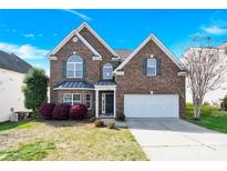 Charming two-story brick home with manicured lawn and attached two-car garage on a beautiful sunny day at 2275 Laurens Dr, Concord, NC 28027