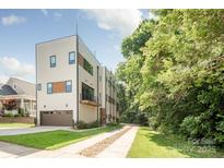Modern three-story townhouse with a neutral facade, balcony, and an attached garage and long driveway at 327 S Turner Ave, Charlotte, NC 28208