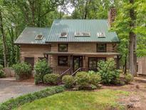 Charming log cabin featuring a metal roof, stone chimney, and cozy front porch at 5109 Walnut Grove Ln, Charlotte, NC 28227