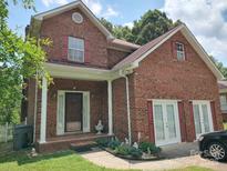 Charming brick home featuring a covered front porch, red shutters, and lush landscaping at 7318 Brighton Brook Dr, Charlotte, NC 28212