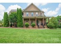 Beautiful two-story brick home boasts a large, well-manicured front lawn and a welcoming covered porch with stately columns at 8137 Caliterra Dr, Charlotte, NC 28227
