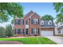 Charming brick home with well-manicured lawn, black shutters, and attached two-car garage at 1220 Elrond Nw Dr, Charlotte, NC 28269