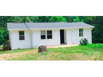 Cozy one-story home featuring white siding and a well-maintained yard, set against a backdrop of lush trees at 129 Williams Rd, Bessemer City, NC 28016