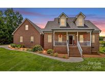 Charming brick home featuring manicured lawn, inviting front porch, and dormer windows at 159 Forest Abbey Ln, China Grove, NC 28023