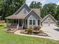 Charming two-story home featuring a welcoming front porch, beautiful landscaping, and a detached two-car garage at 179 Delwood Ct, Mount Gilead, NC 27371